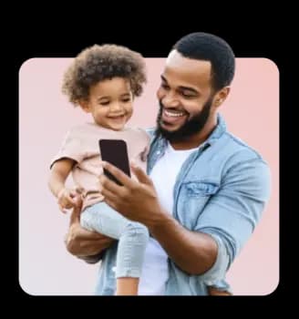 Smiling father holding child and looking at smartphone, representing users finding financial solutions